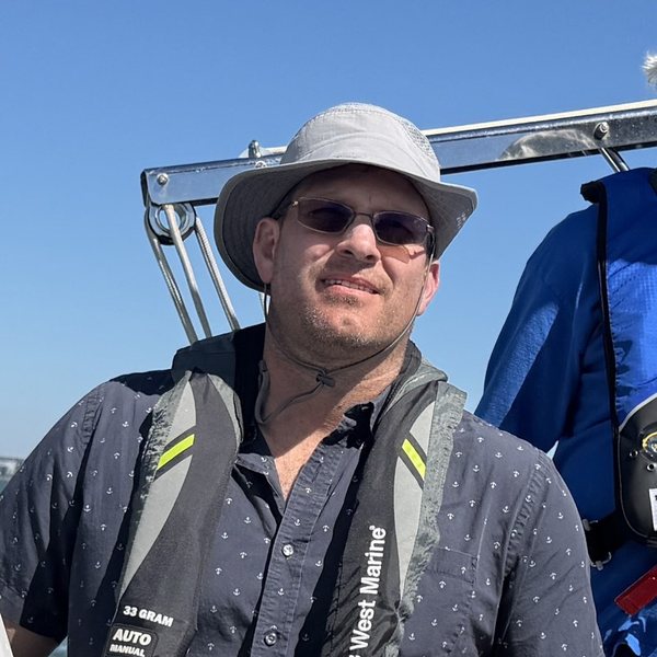 Michael Schuck at the helm of a sailboat on San Francisco Bay